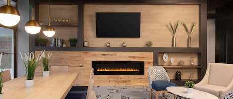 A modern living room with a fireplace, a flat-screen TV, and comfortable seating.