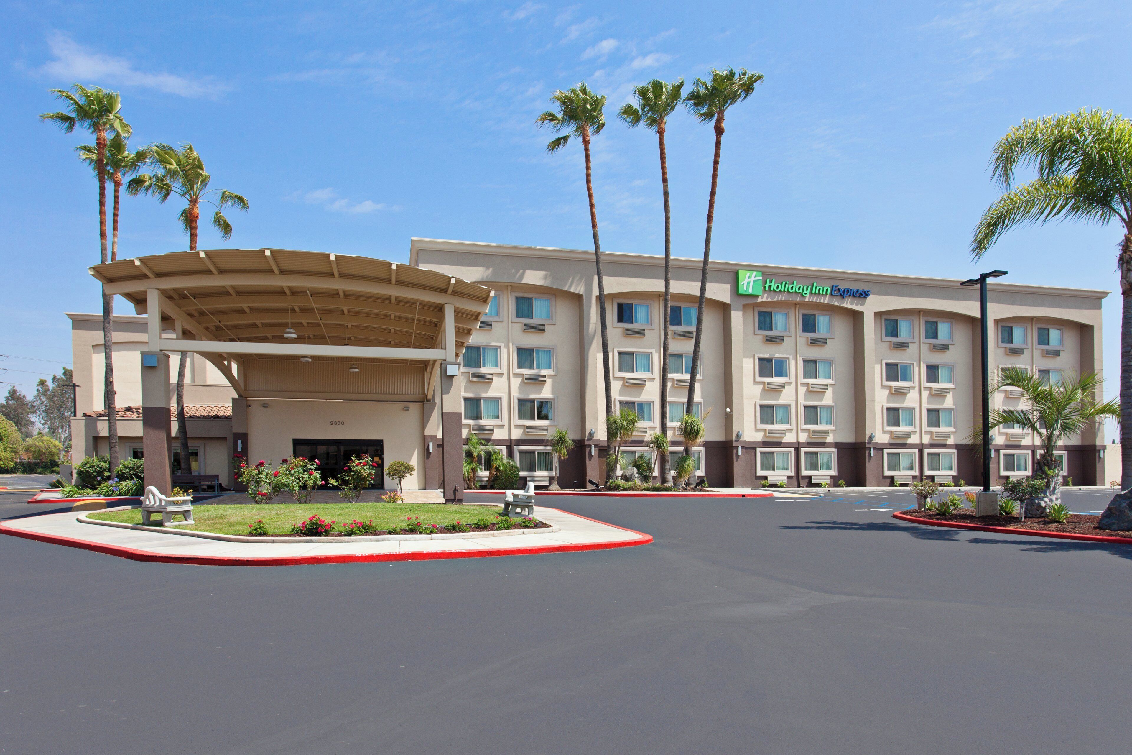 A Holiday Inn Express hotel with a covered entrance, palm trees, and a parking lot.