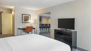 A hotel room with a large bed, a desk with a chair, a television, and a dining area visible through an open door. - Holiday Inn Express San Bernardino - Colton by IHG (Colton)