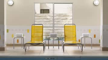 Una piscina techada, sillones reclinables de piscina