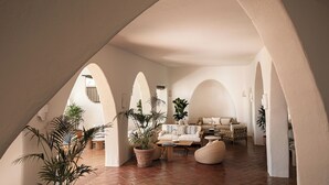 An interior with arched ceilings, a seating area with sofas and chairs, and potted plants. - Romazzino, A Belmond Hotel, Costa Smeralda (Arzachena)