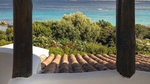 A view through wooden pillars to a coastal landscape with a mountain in the distance. - Romazzino, A Belmond Hotel, Costa Smeralda (Arzachena)