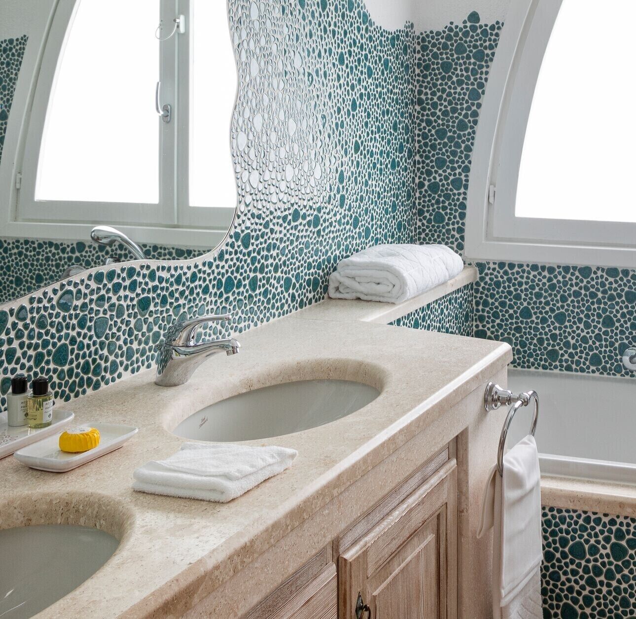 A bathroom with a freestanding bathtub, a sink with a marble countertop, and mosaic tile walls.