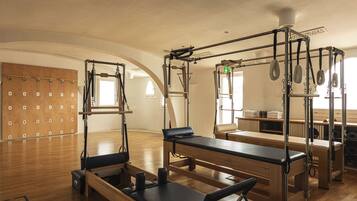 A Pilates studio with wooden floors, exercise equipment, and a wooden wall with hooks.