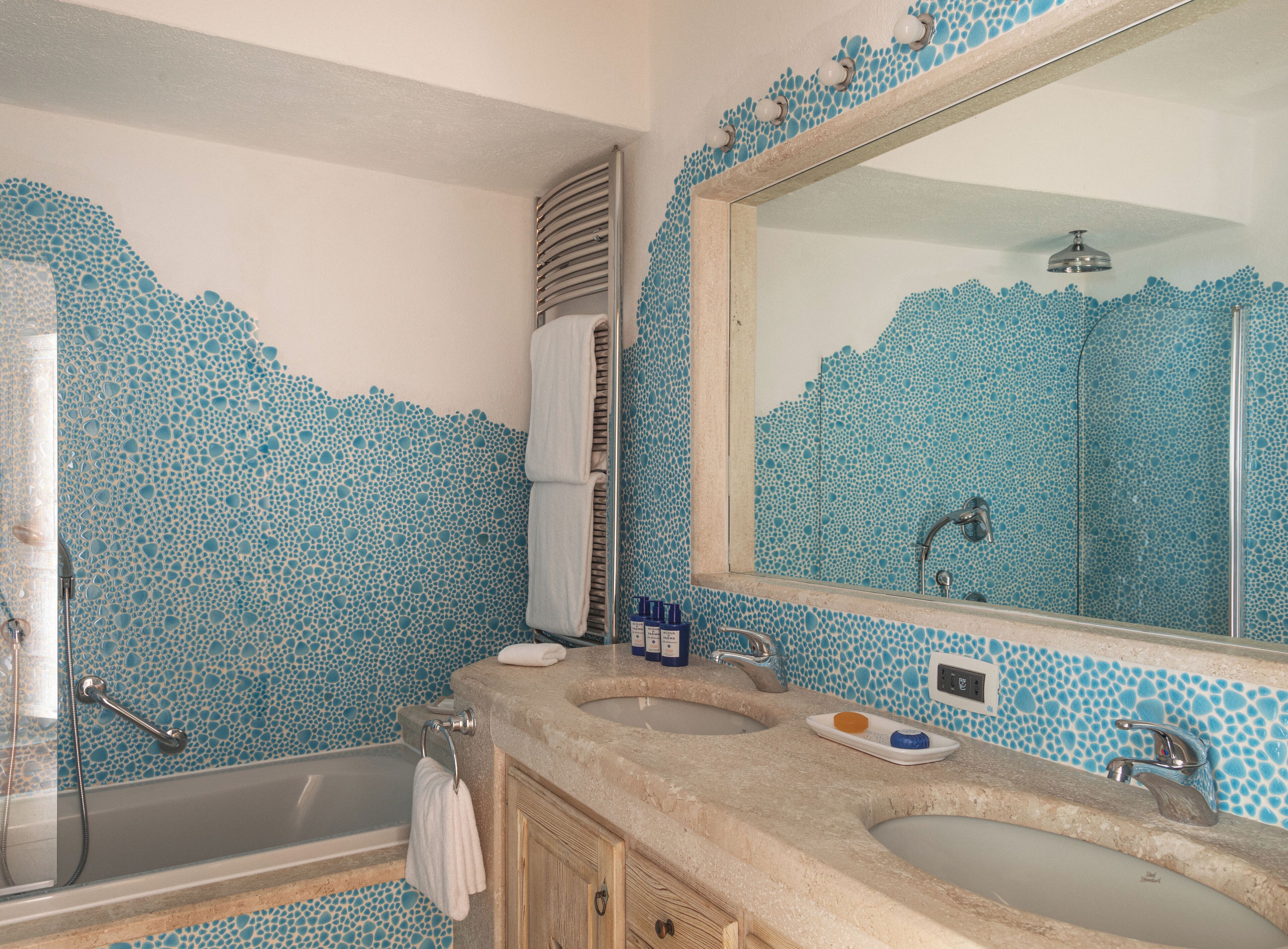 Un baño con un espejo grande, dos lavamanos, una bañera y una ducha.