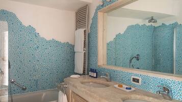 Un baño con un espejo grande, dos lavamanos, una bañera y una ducha.