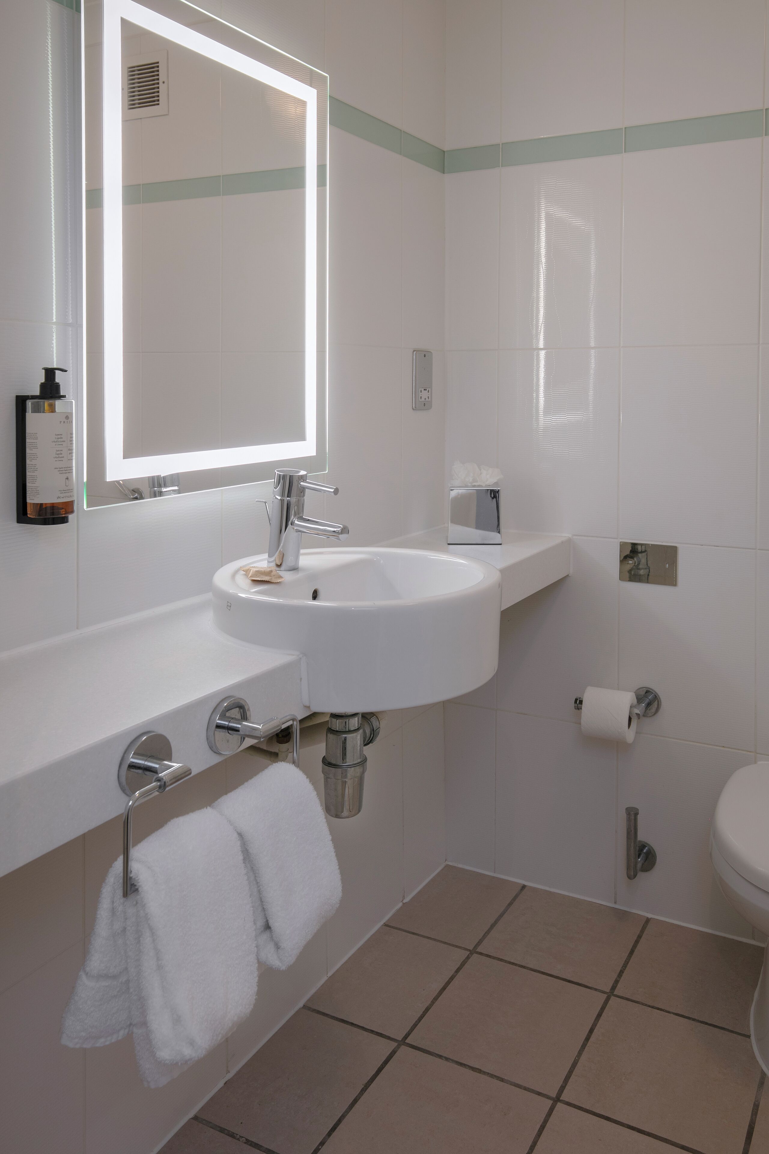 A bathroom with a white sink, mirror, and toilet.
