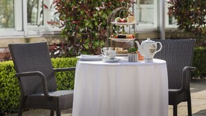 A table set with a tiered tea service, two wicker chairs, and a white tablecloth. - The Park Royal Hotel & Spa (Warrington)