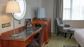 Una habitación de hotel con un escritorio de madera, un televisor, una silla y una cama.