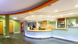 A hotel lobby with a reception desk, a sports memorabilia display, and a refrigerator stocked with beverages. - The Park Royal Hotel & Spa (Warrington)