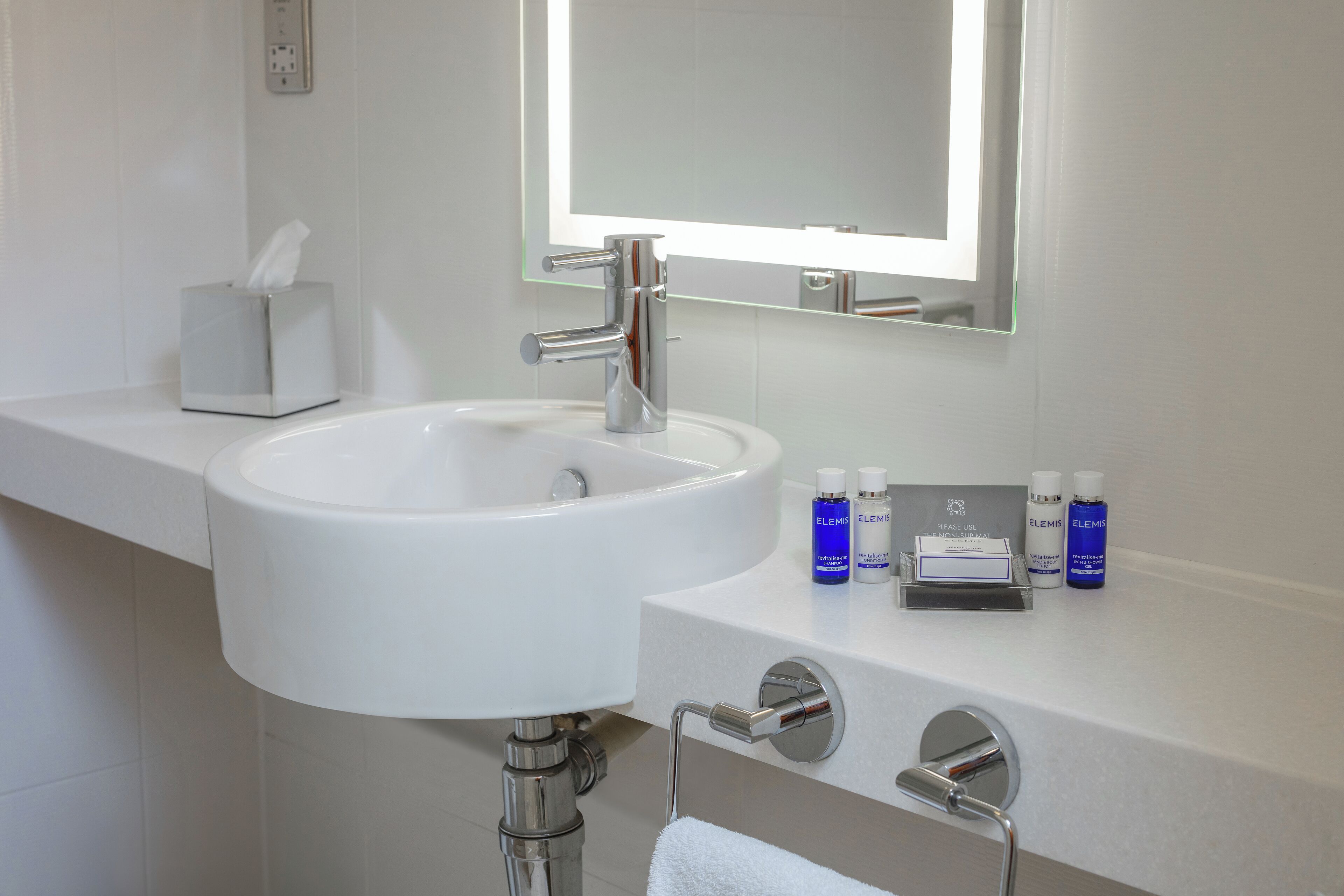 A modern bathroom with a white sink, chrome fixtures, and a mirror above.