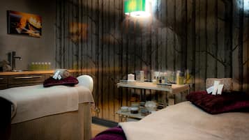 Relax in a serene spa room with two massage tables, a selection of spa products, and a soothing ambiance.