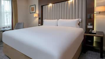 A large bed with a headboard, bedside lamps, and a bedside table with a phone.