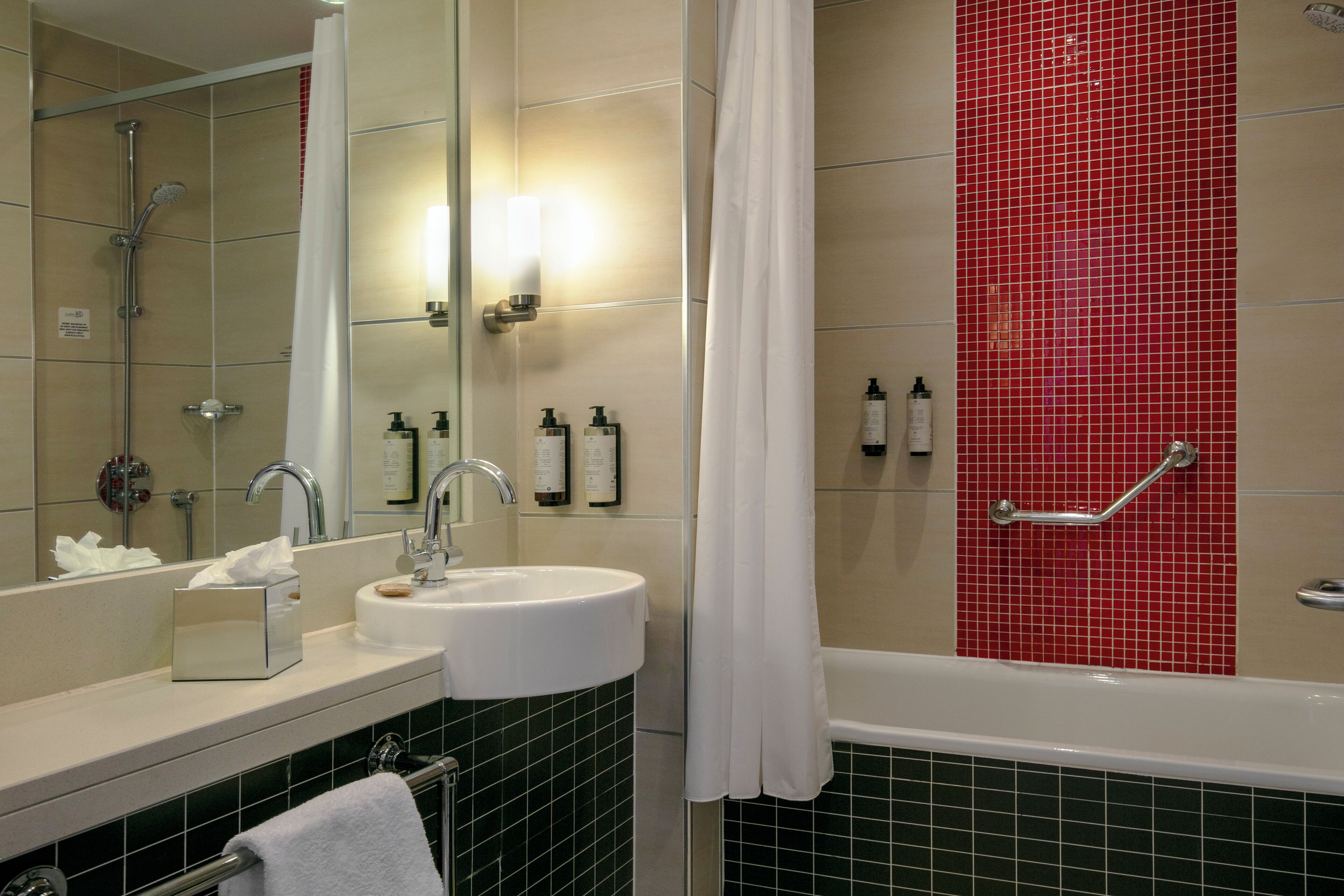 A bathroom with a sink, mirror, shower, and bathtub.