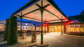 A hotel entrance with a covered patio, stone bollards, and a brick pathway leading to the entrance. - The Park Royal Hotel & Spa (Warrington)