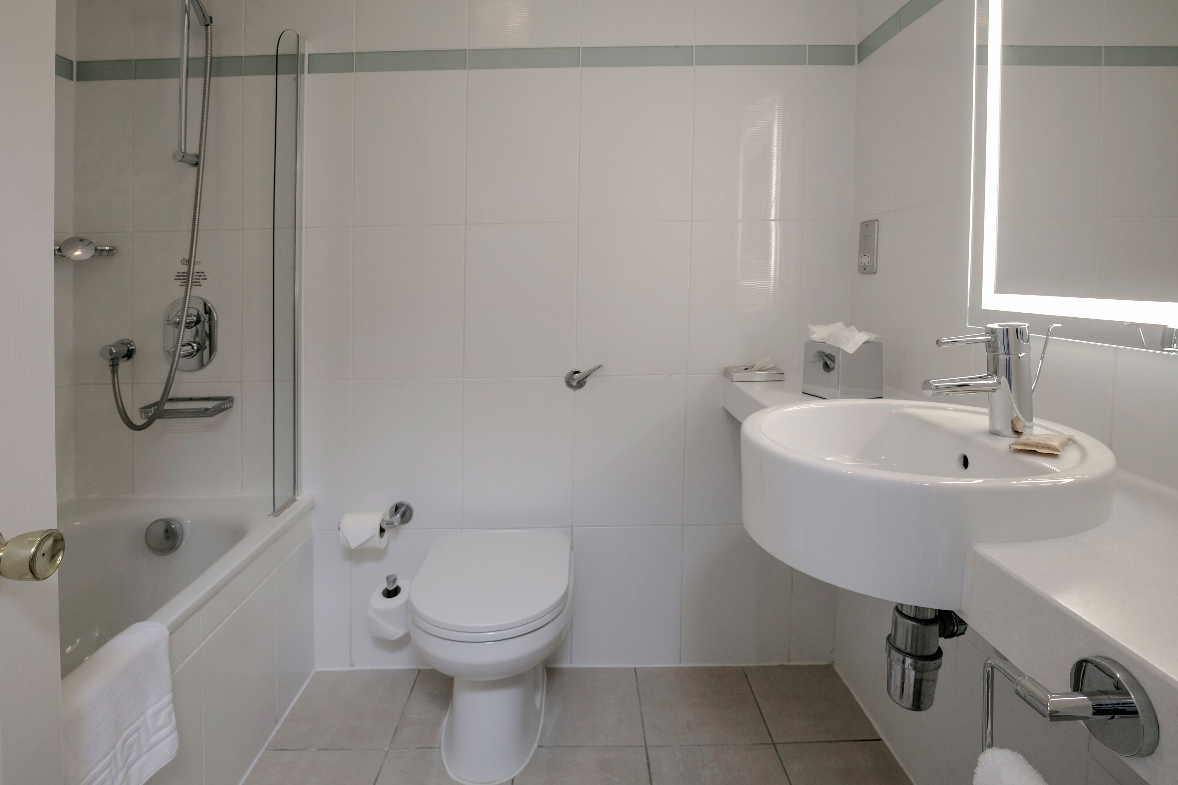 Et badeværelse med badekar, toilet og håndvask.