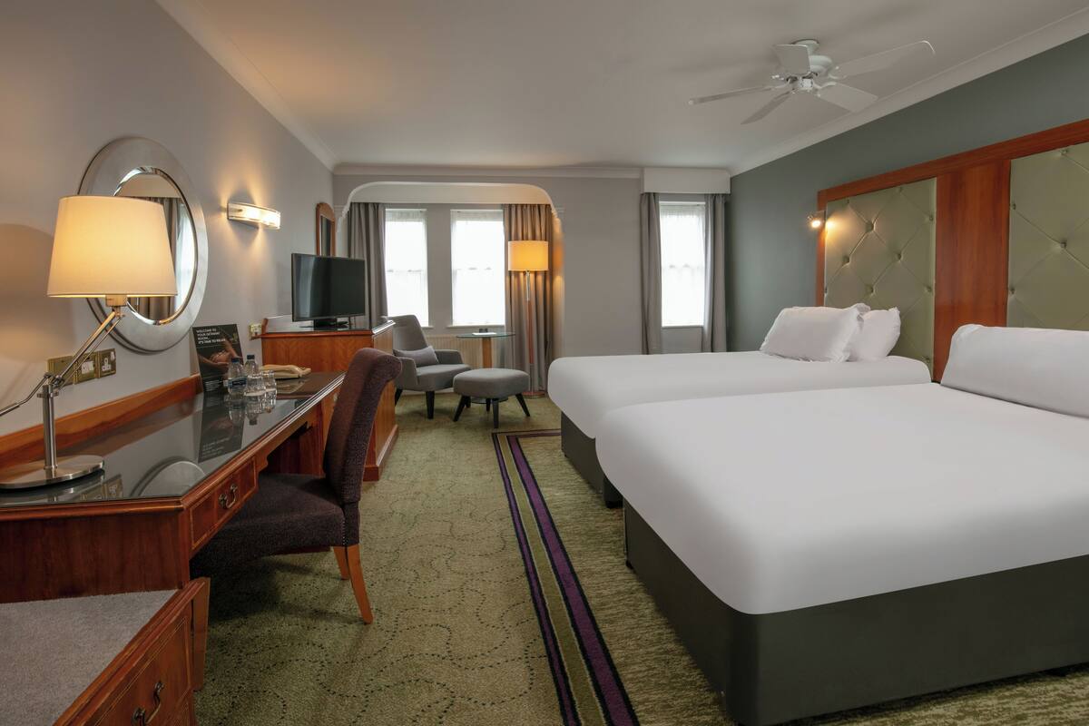 A hotel room with a bed, desk, chair, television, and a ceiling fan.