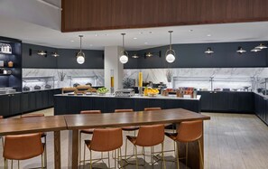A modern kitchen with a marble backsplash, a central island with bar stools, and a buffet area. - Hilton Atlanta Airport (Atlanta)