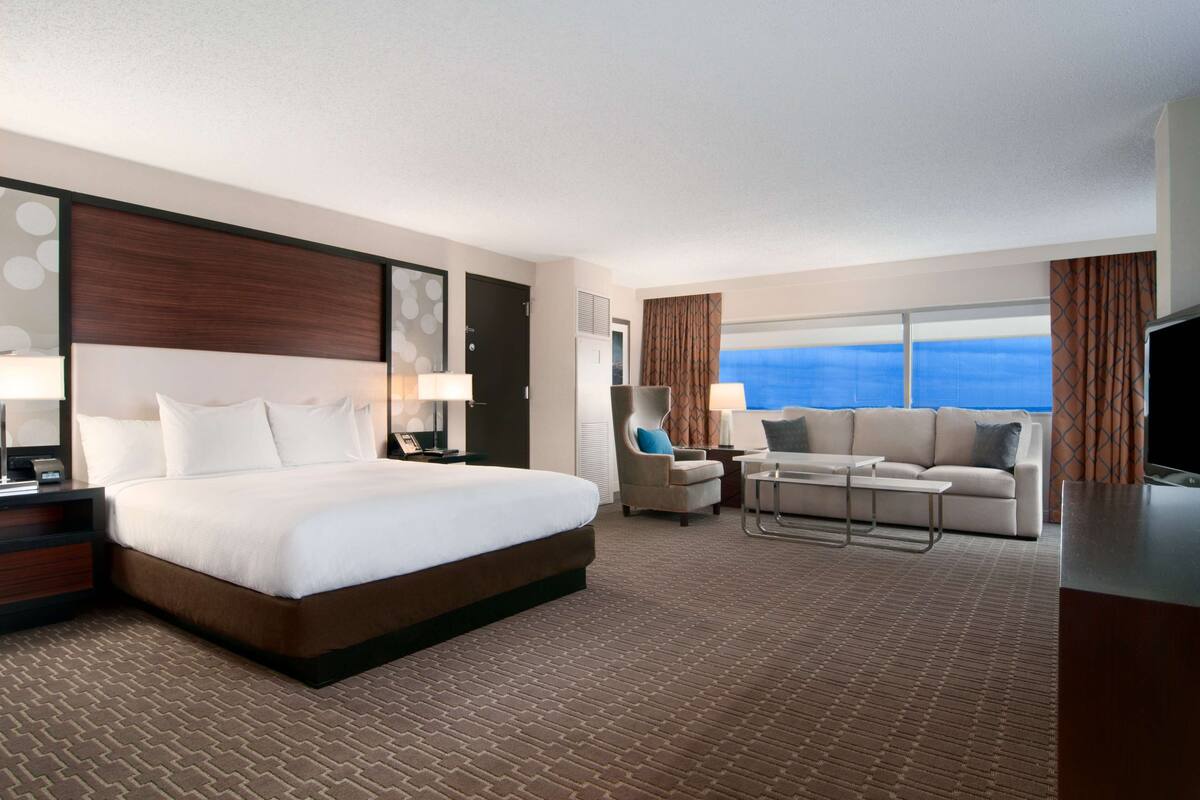 Una habitación de hotel con una cama grande, un sofá, una silla y un televisor.