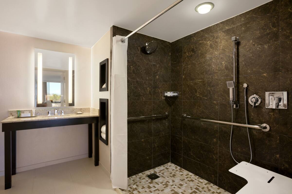 Un baño moderno con ducha, inodoro y tocador con espejo.