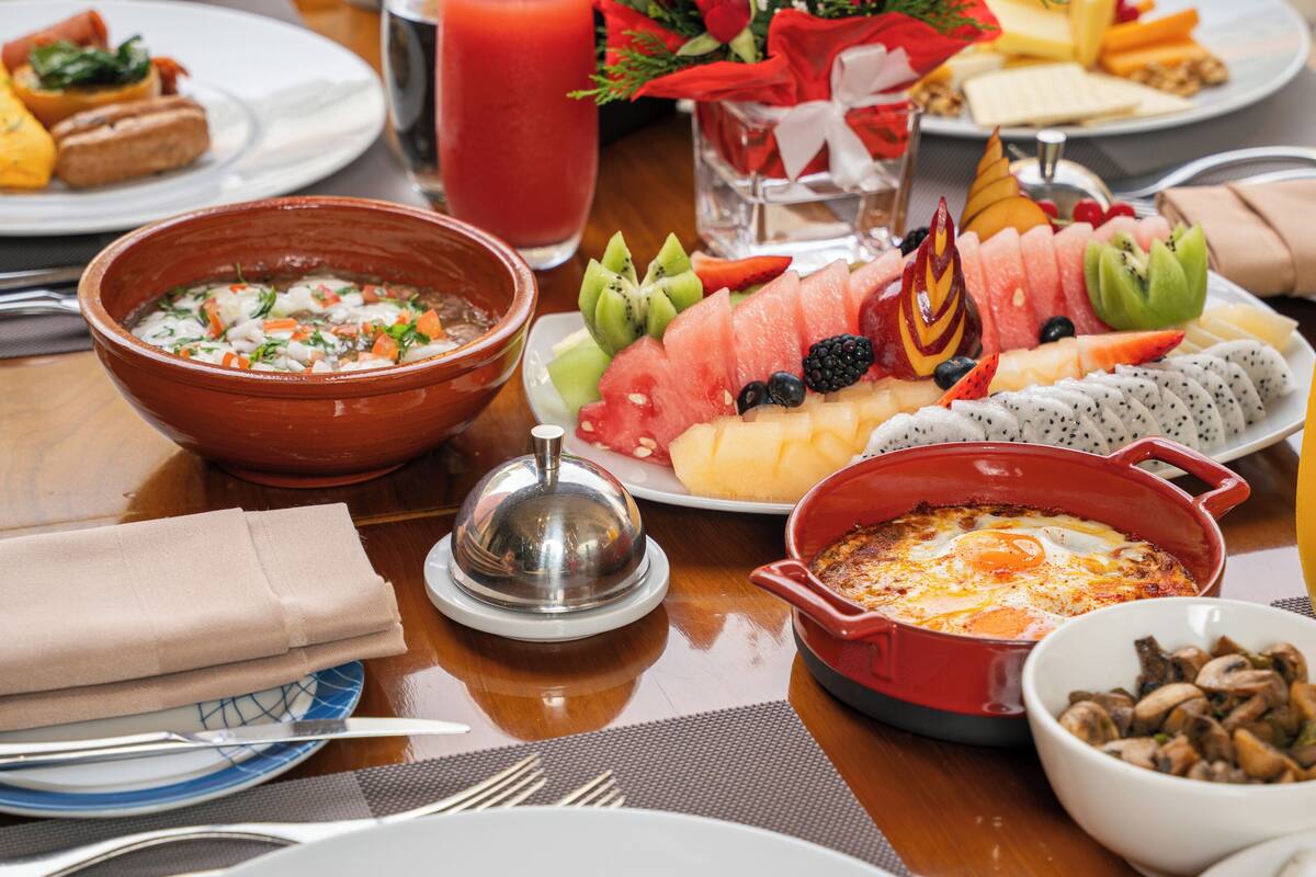Una mesa dispuesta con diferentes platos, incluyendo una ensalada, una bandeja de frutas y un tazón de sopa.