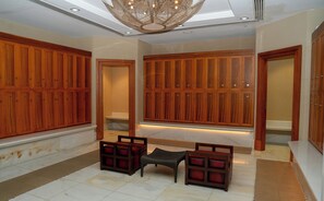 A spacious hallway with wooden paneling, a seating area with a small table and chairs, and a ceiling with a skylight and decorative lighting.