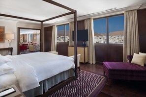 Une chambre d’hôtel avec un grand lit, un canapé, une télévision et une vue sur le paysage urbain.