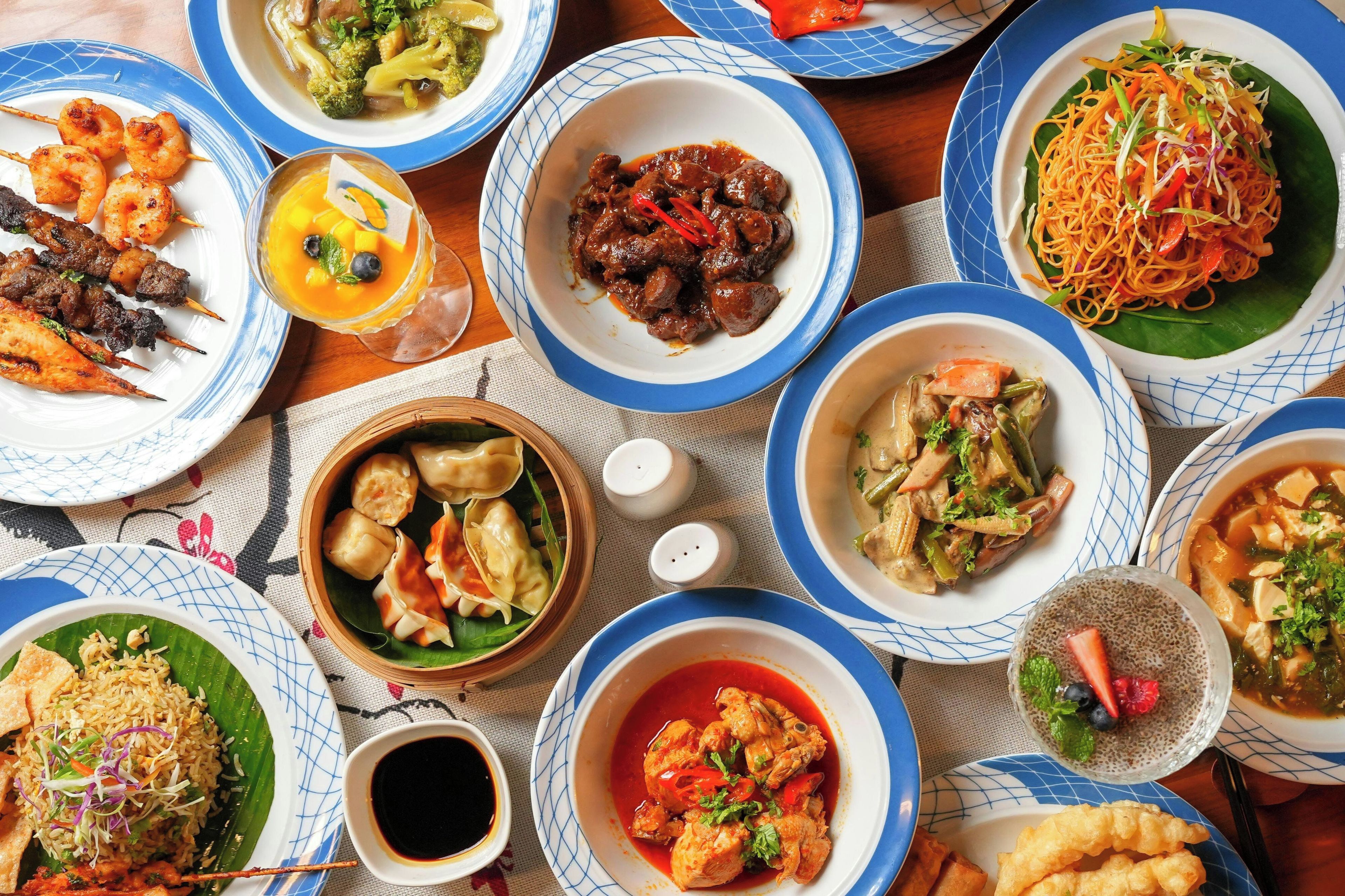 A variety of dishes on a table, including skewered meat, dumplings, and a bowl of soup.
