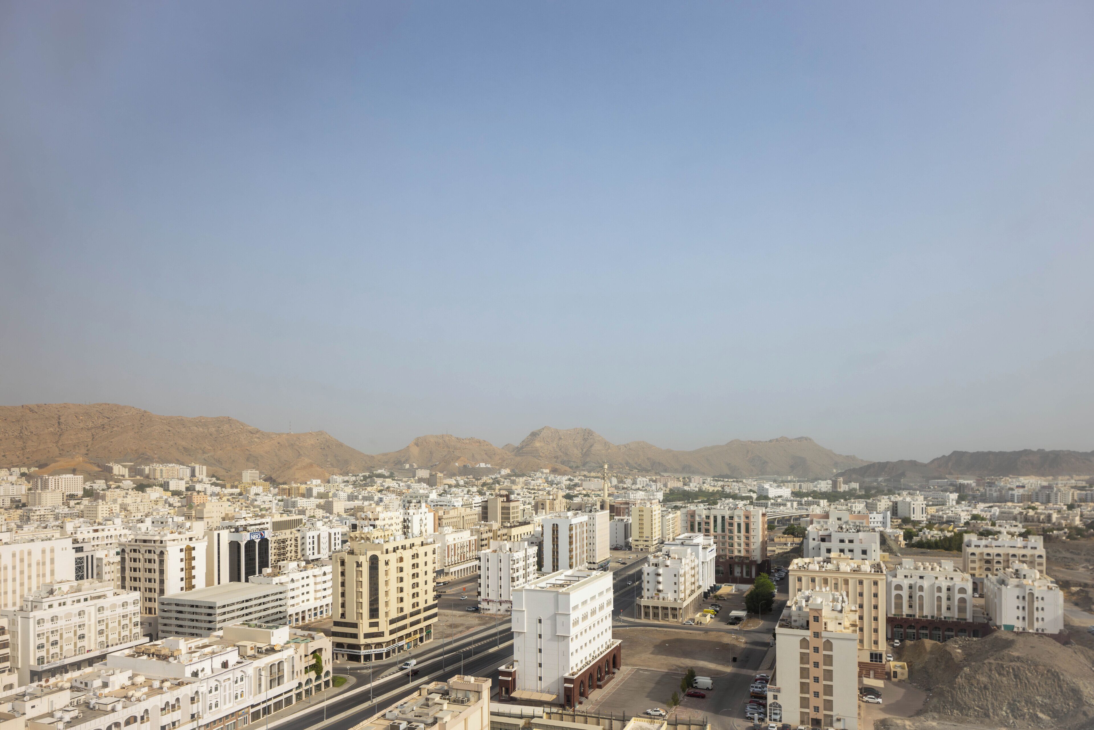 A cityscape with numerous buildings, roads, and a mountainous backdrop.
