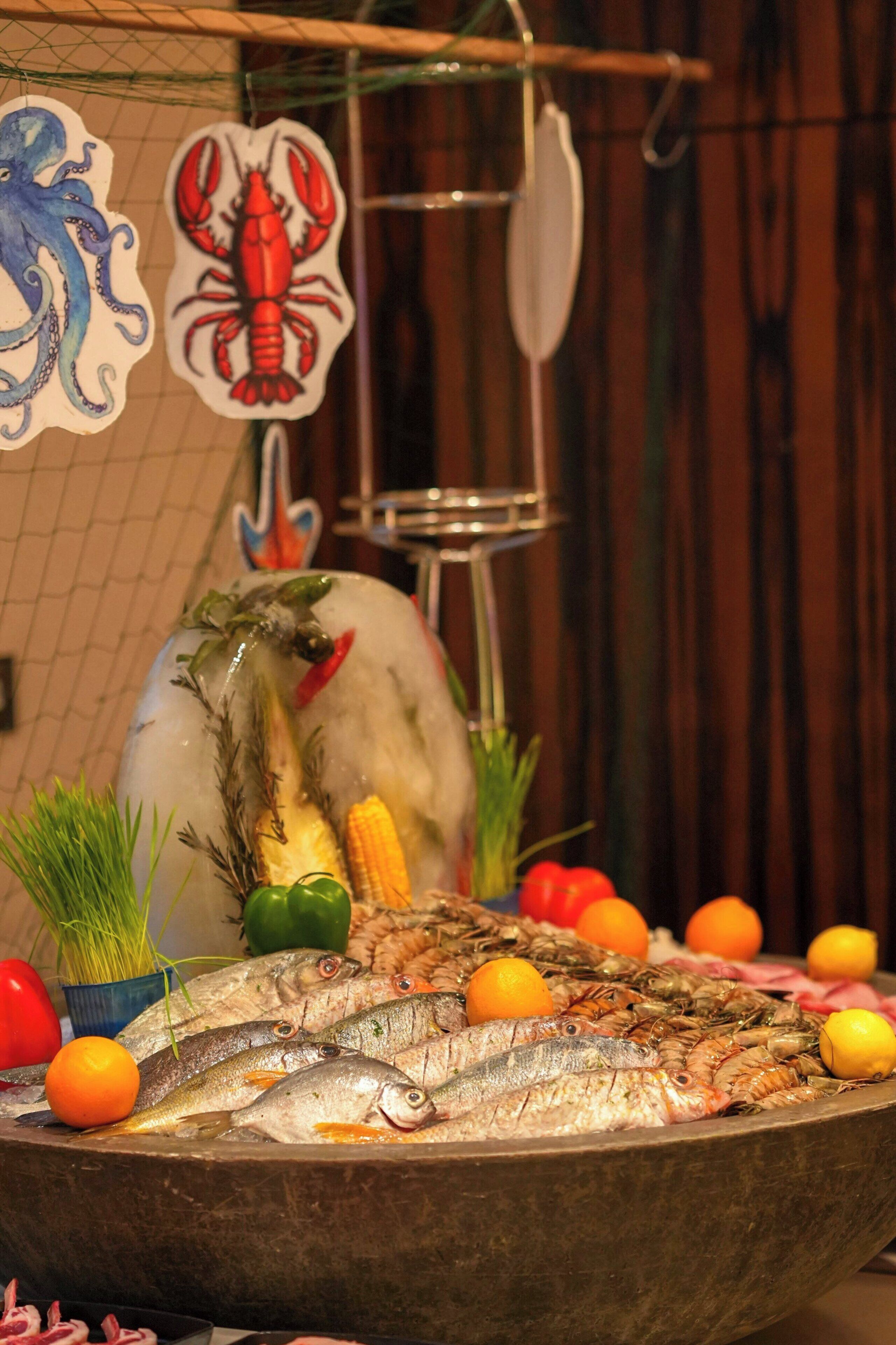A seafood display with various fish and shrimp, garnished with vegetables and citrus fruits.