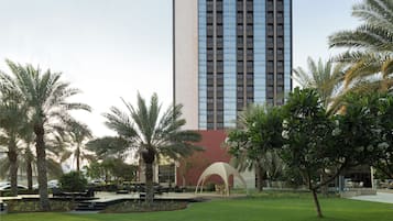 Un edificio moderno con un llamativo logo en forma de 'S', rodeado de un césped cuidado y palmeras.