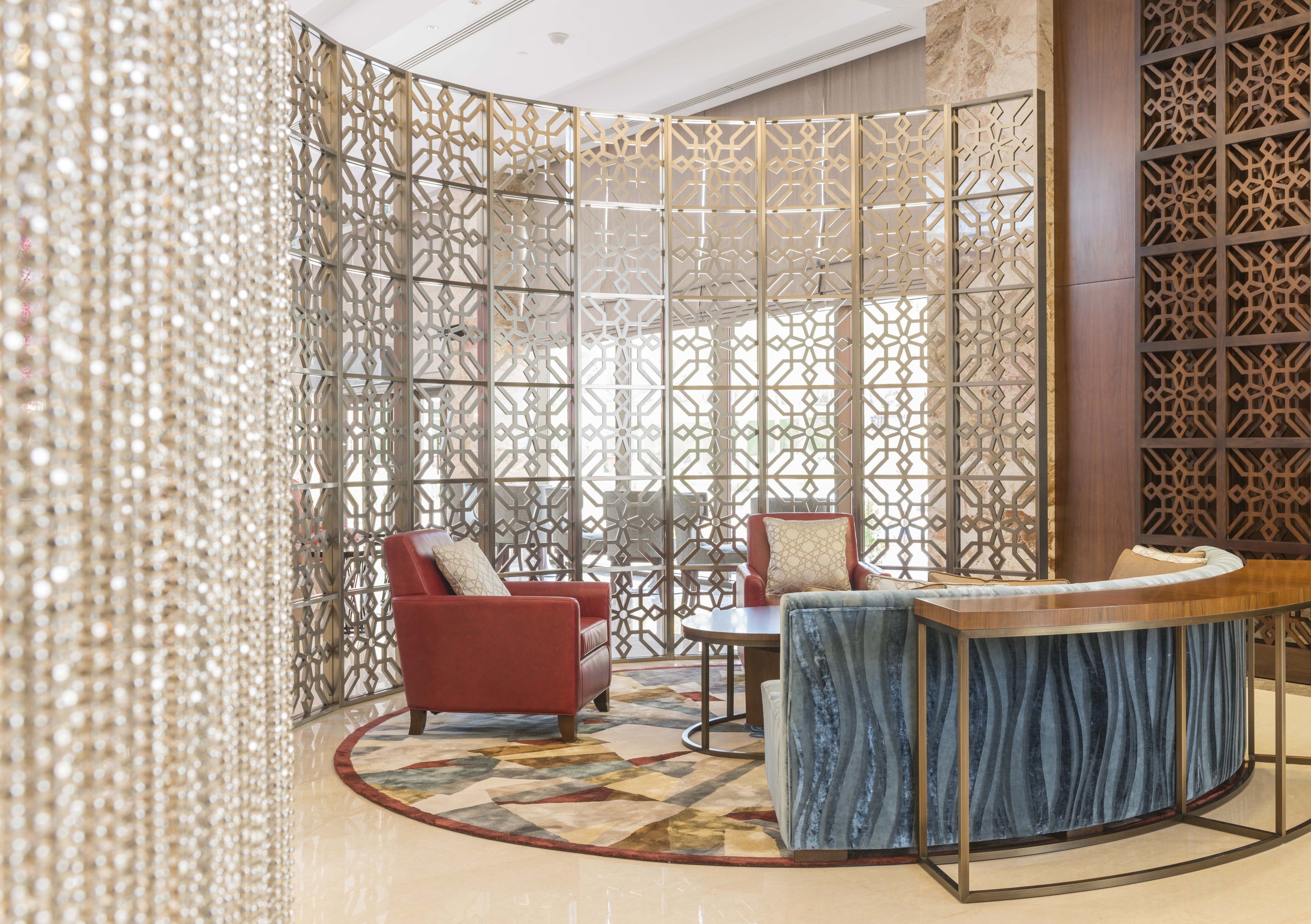 A modern interior with a curved seating area, a round table, and a decorative partition with intricate patterns.