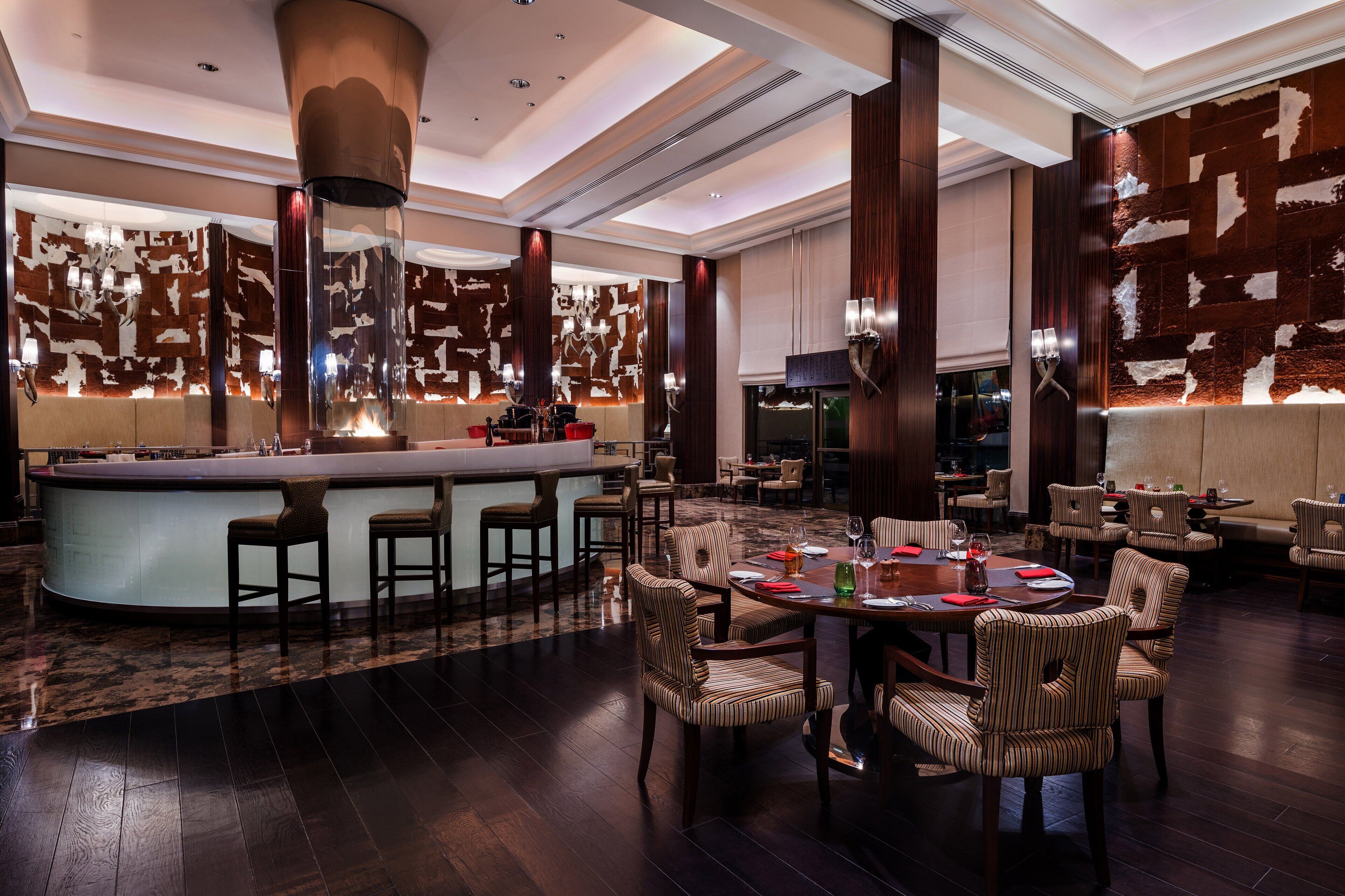 A spacious restaurant with a central bar, high ceilings, and modern decor.
