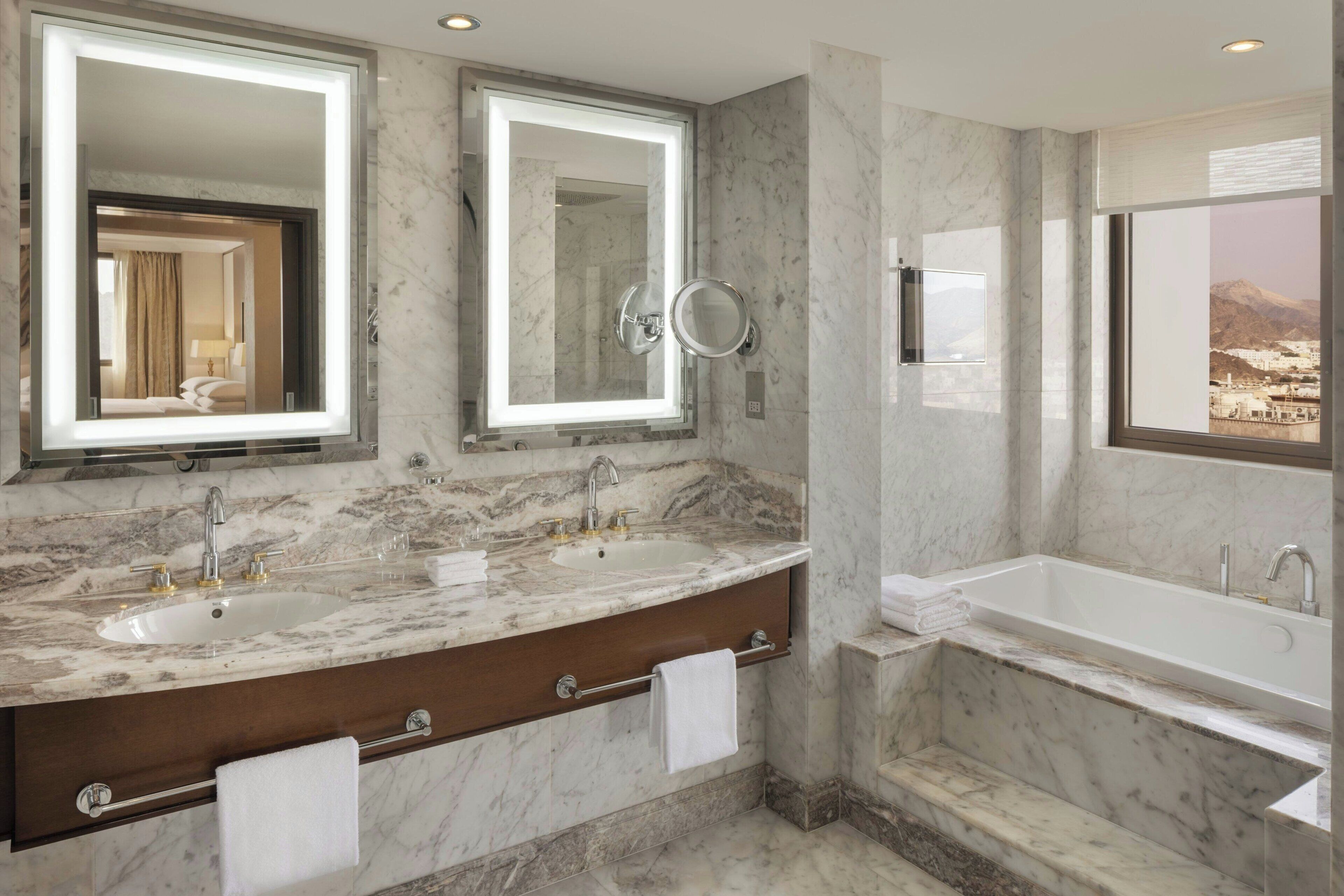 Une salle de bain avec deux lavabos, une baignoire et de grands miroirs.