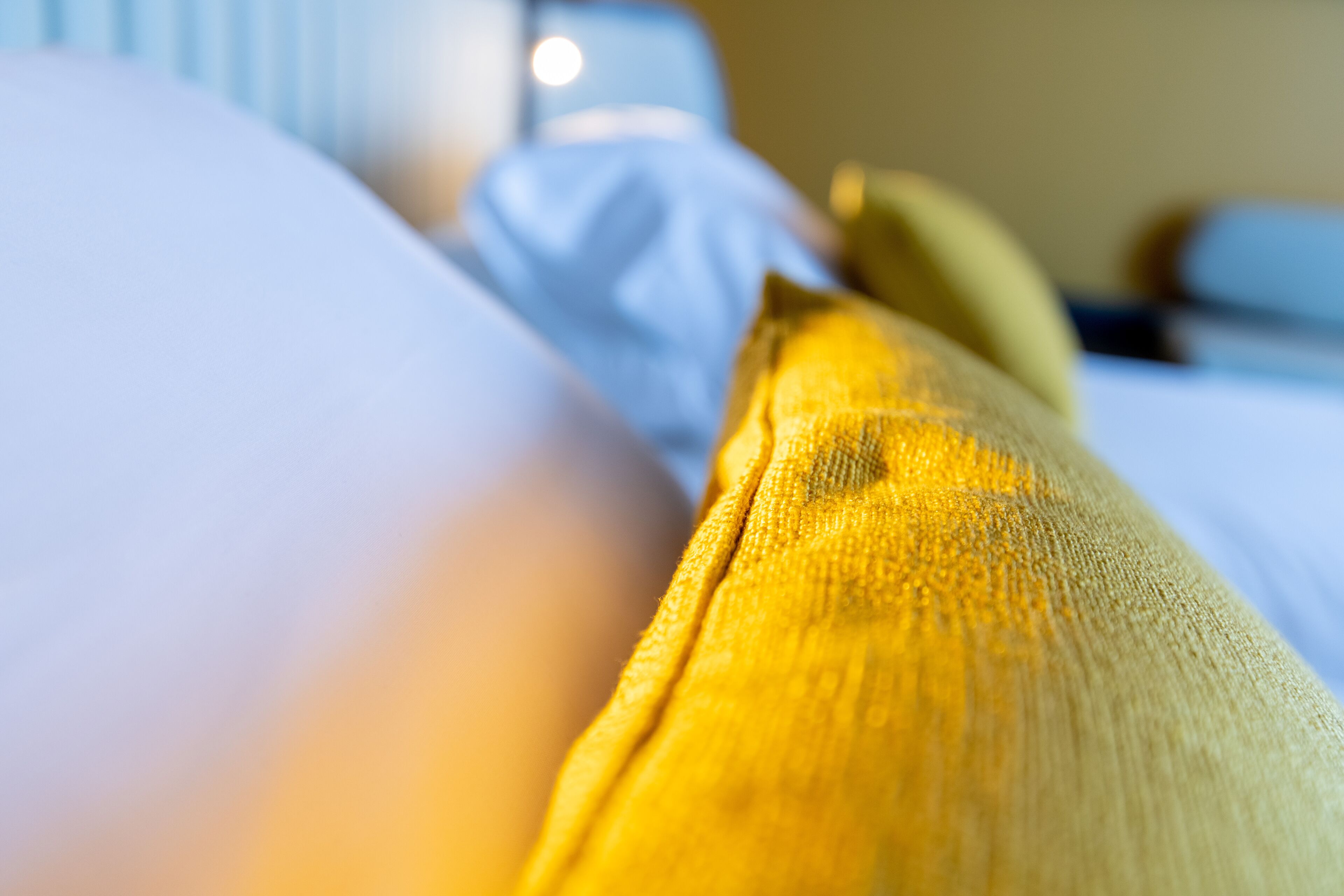 A close-up of a bed with a yellow and blue blanket.
