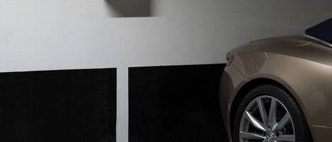 Un garaje para coches con un automóvil, una cámara de seguridad y un panel de control en la pared.