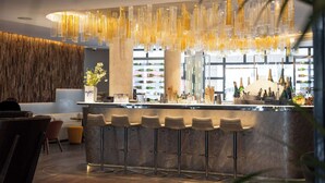 A modern bar area with a central bar counter, multiple stools, and a decorative hanging light fixture. - Best Western Premier Hôtel de la Paix (Reims)