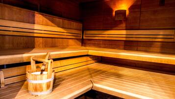 A sauna with wooden benches and a wooden bucket.