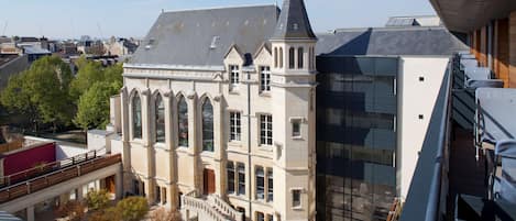 A historic building with a prominent tower and a modern glass extension.