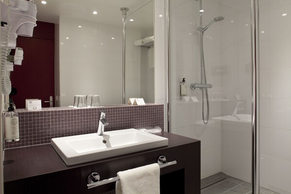 A modern bathroom with a large mirror, a white sink, and a glass-enclosed shower. - Best Western Premier Hôtel de la Paix (Reims)