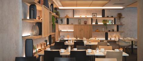 A modern dining area with multiple tables, chairs, and shelves with decorative items.