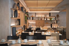 A modern dining area with multiple tables, chairs, and shelves with decorative items. - Best Western Premier Hôtel de la Paix (Reims)