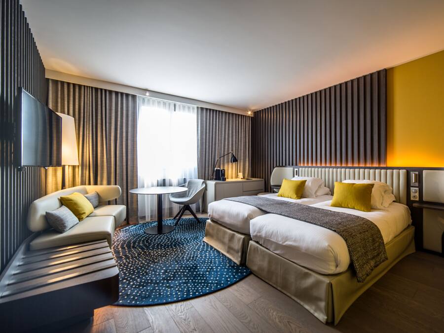 Una habitación de hotel moderna con cama, sofá, escritorio y televisor.