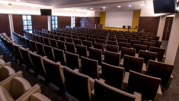 En teater med rader av sittplatser, en scen med en skärm och ett projektionssystem.