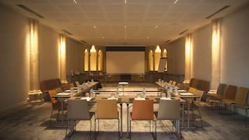 Une salle de conférence avec une longue table, des chaises, un écran de projection et un sol recouvert de moquette.