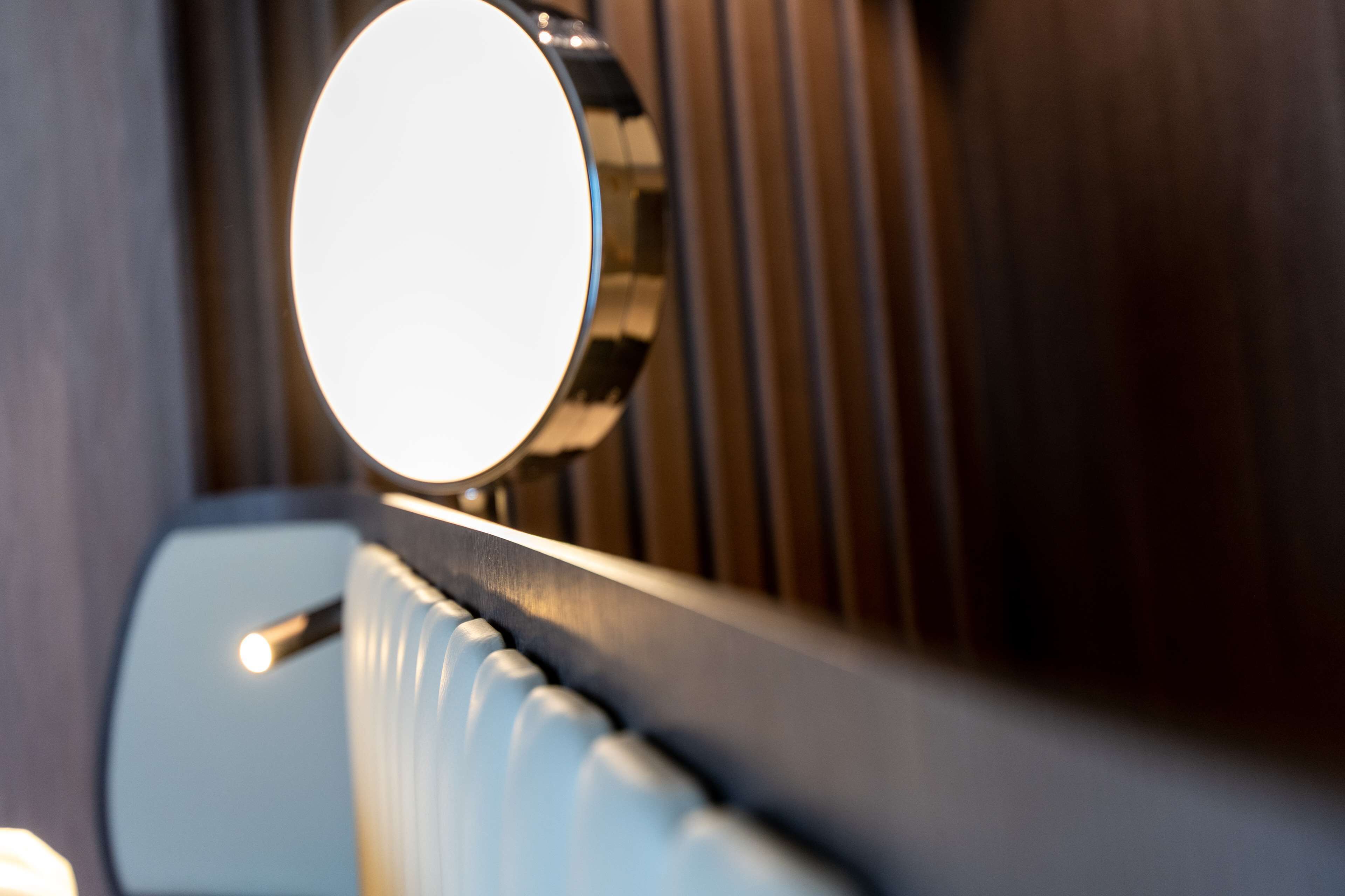 Een close-up van een wandlamp met een ronde spiegel.