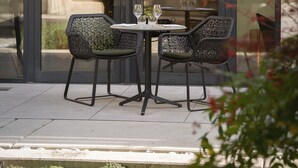 An outdoor seating area with two chairs and a table, a glass partition, and a view of greenery and buildings. - Best Western Premier Hôtel de la Paix (Reims)