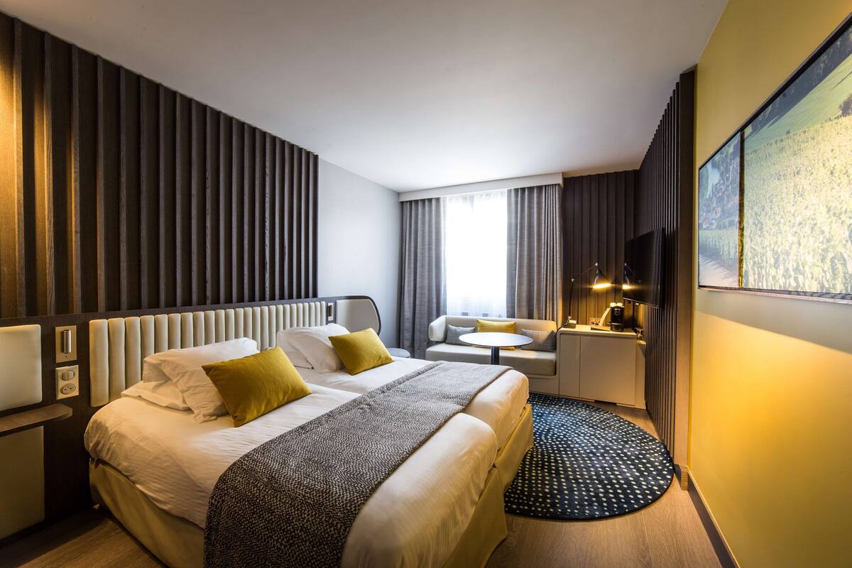 Moderni hotellihuone, jossa on suuri sänky, sohva, pieni pöytä ja televisio.