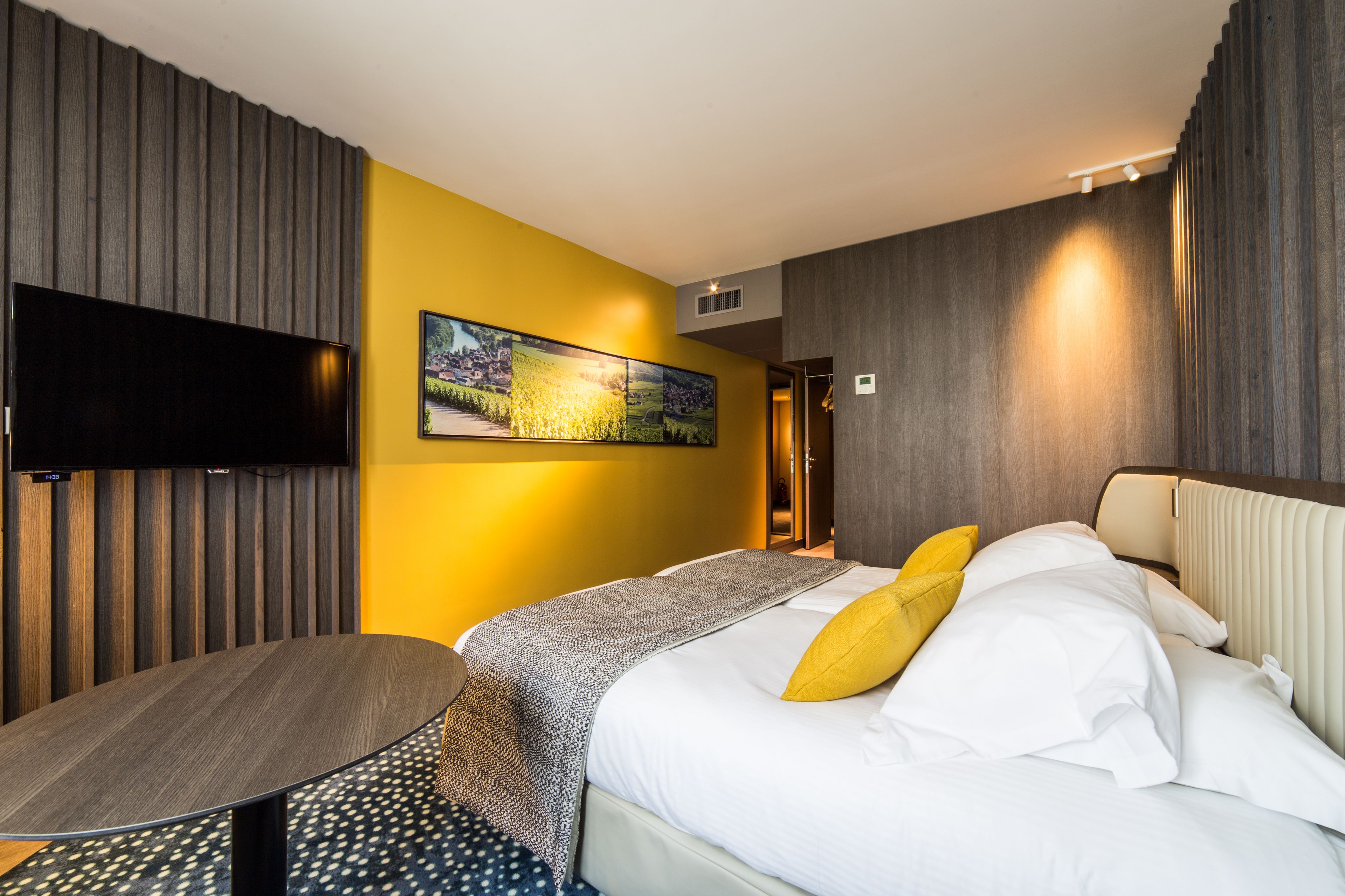 Een hotelkamer met een bed, een televisie, een schilderij en een bureau.