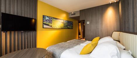 Een hotelkamer met een bed, een televisie, een schilderij en een bureau.